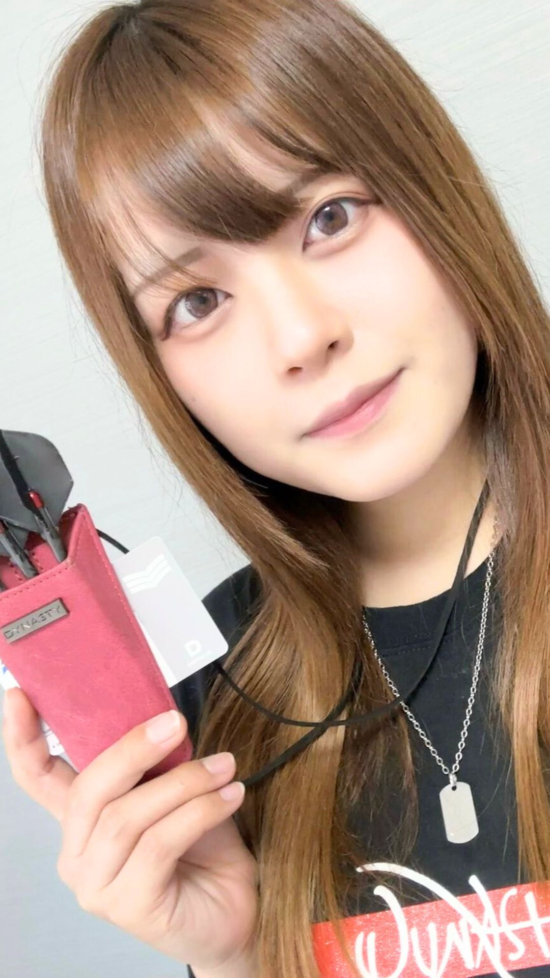 ダーツケースを手に持ち微笑む女性プロダーツプレイヤー中谷祐里プロ。落ち着いた雰囲気と優しいまなざし