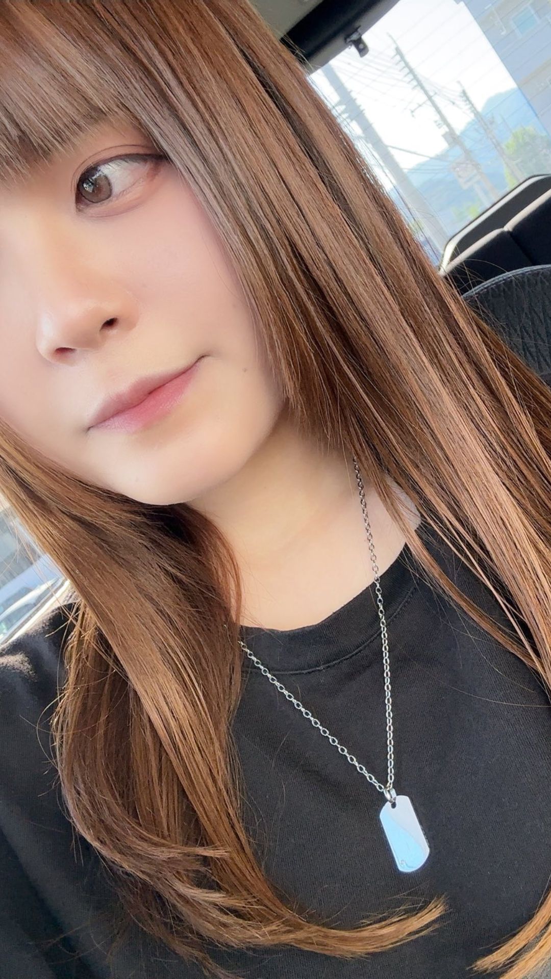 車内で遠くを見つめる女性プロダーツプレイヤー中谷祐里プロ。カジュアルな私服と自然体の表情