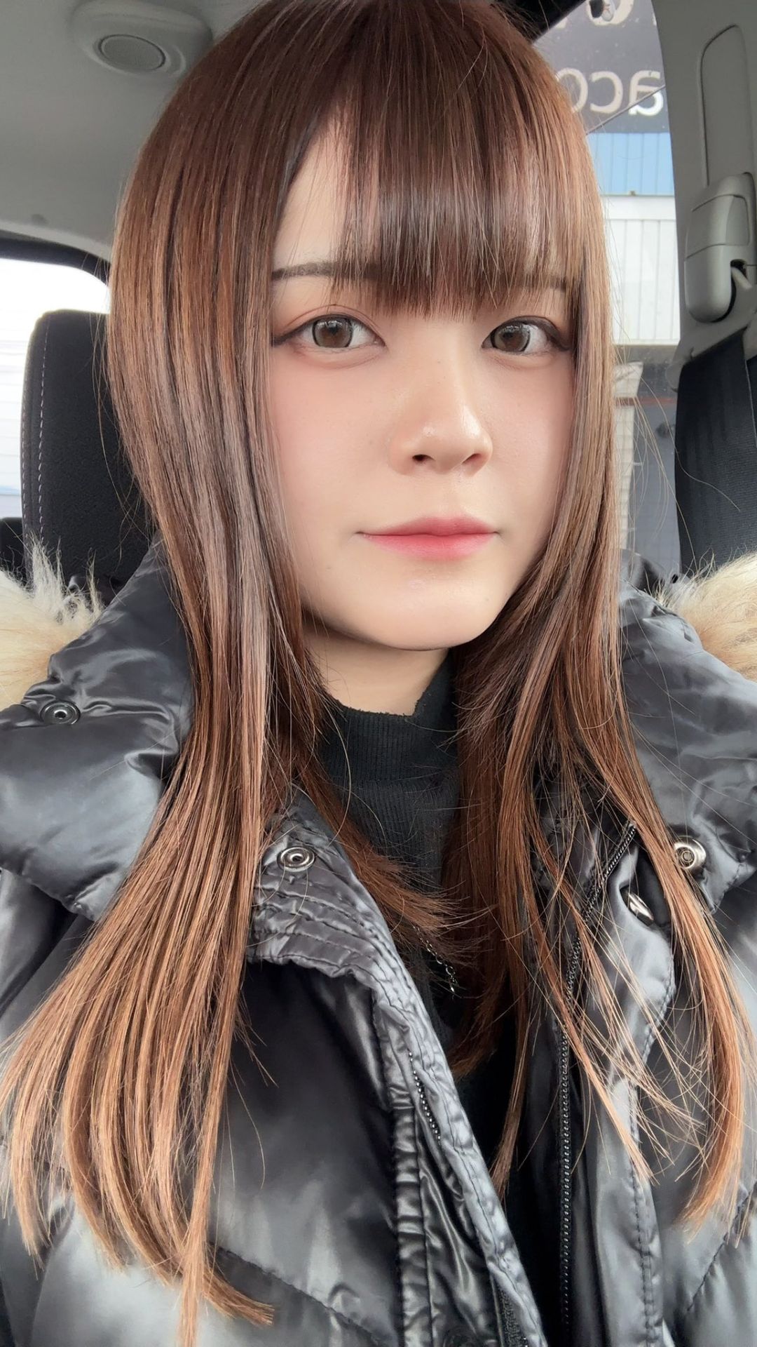 冬のコート姿で車内にいる女性プロダーツプレイヤー中谷祐里プロ。ナチュラルな美しさが際立つポートレート