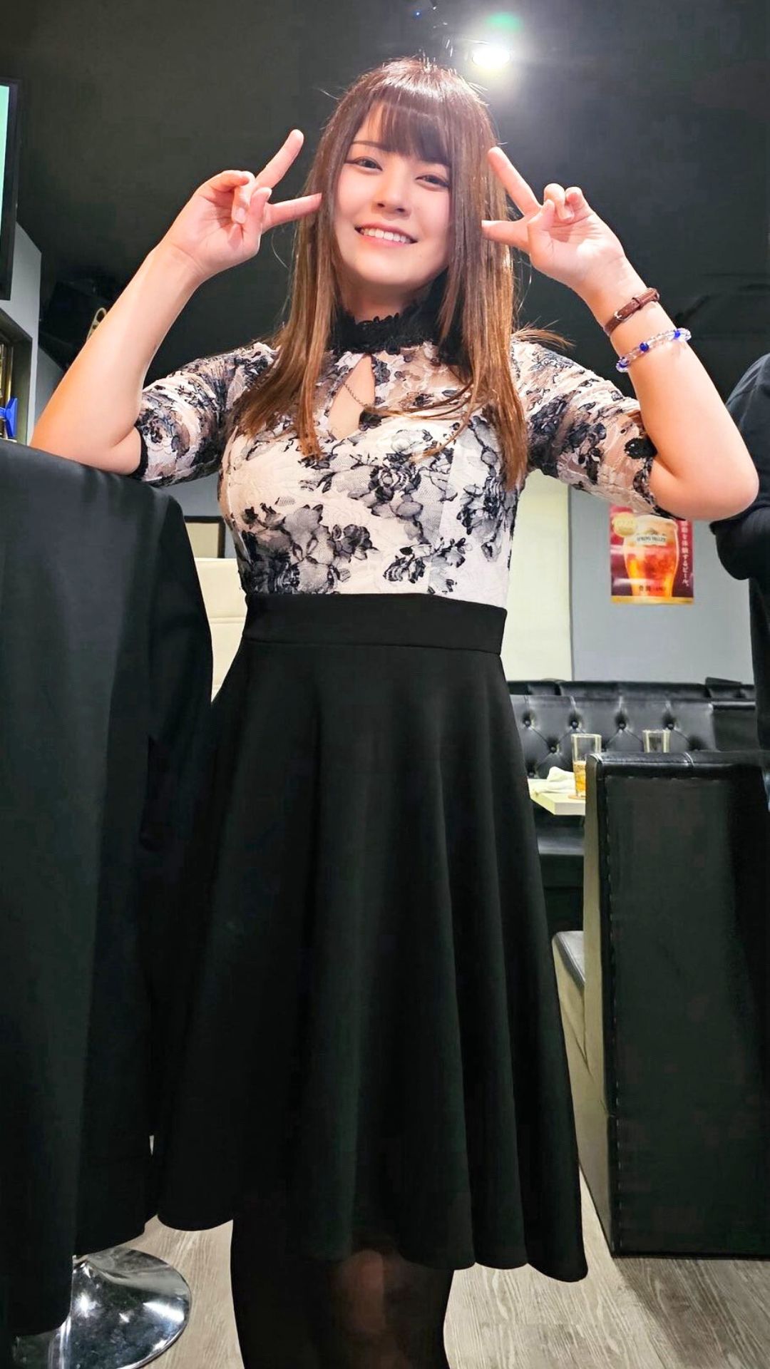 パーティードレス姿でダブルピースをする女性プロダーツプレイヤー中谷祐里プロ。明るく華やかな雰囲気