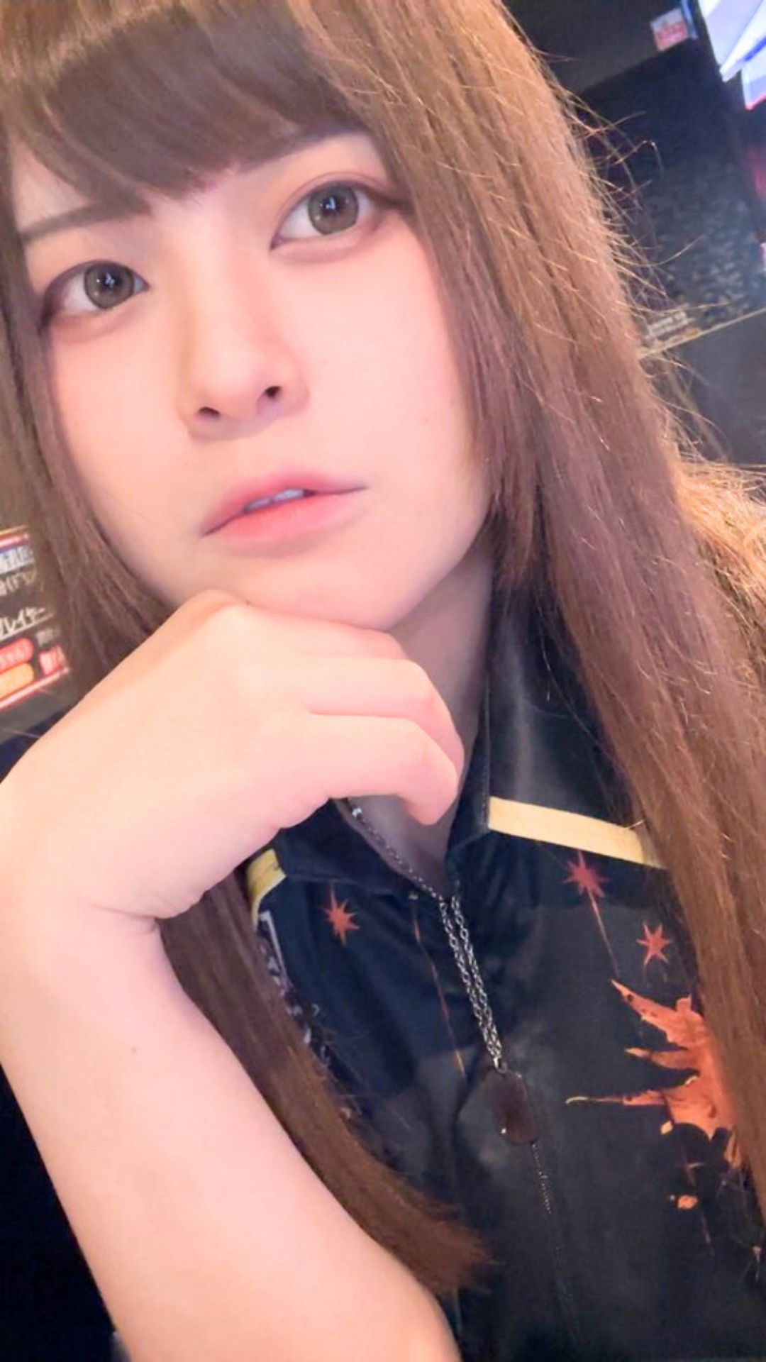 ユニフォーム姿で顎に手を添え、知的な表情を見せる女性プロダーツプレイヤー中谷祐里プロ。落ち着いた雰囲気のポートレート