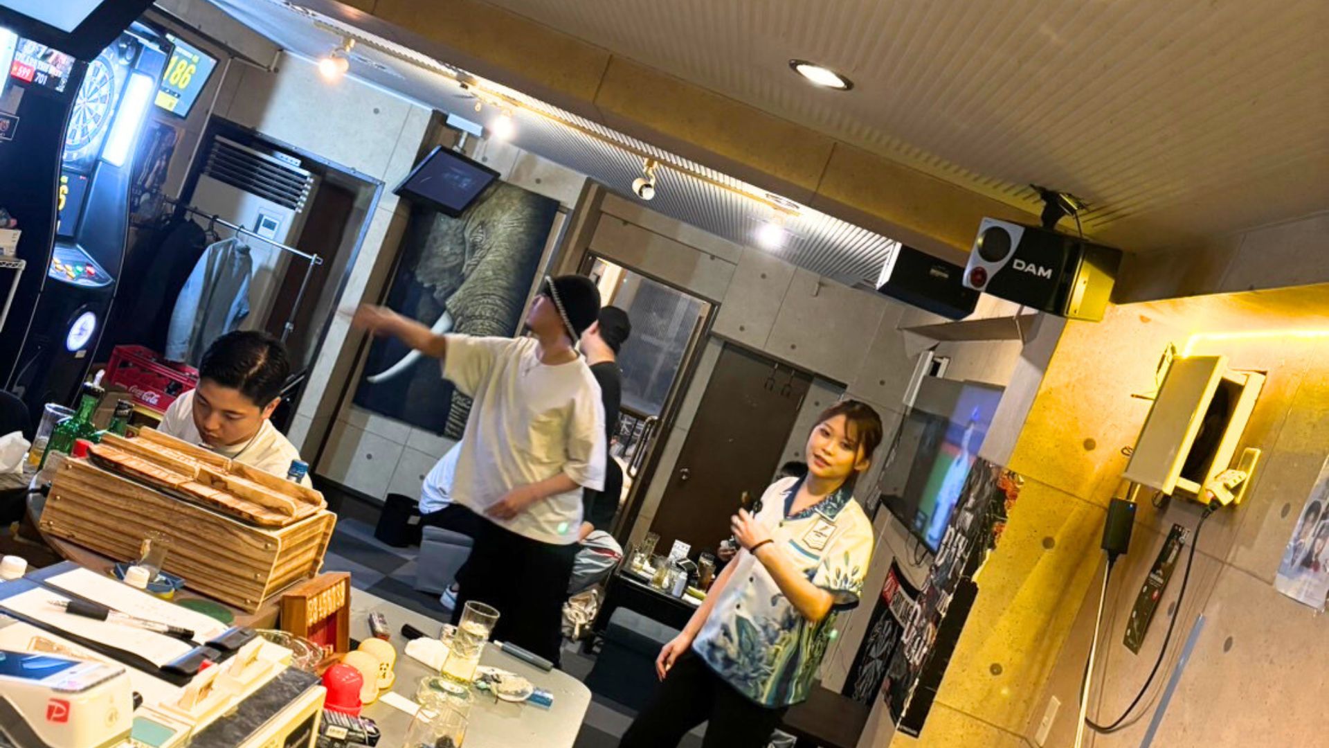 ダーツを投げる男性とスタッフが楽しむ様子