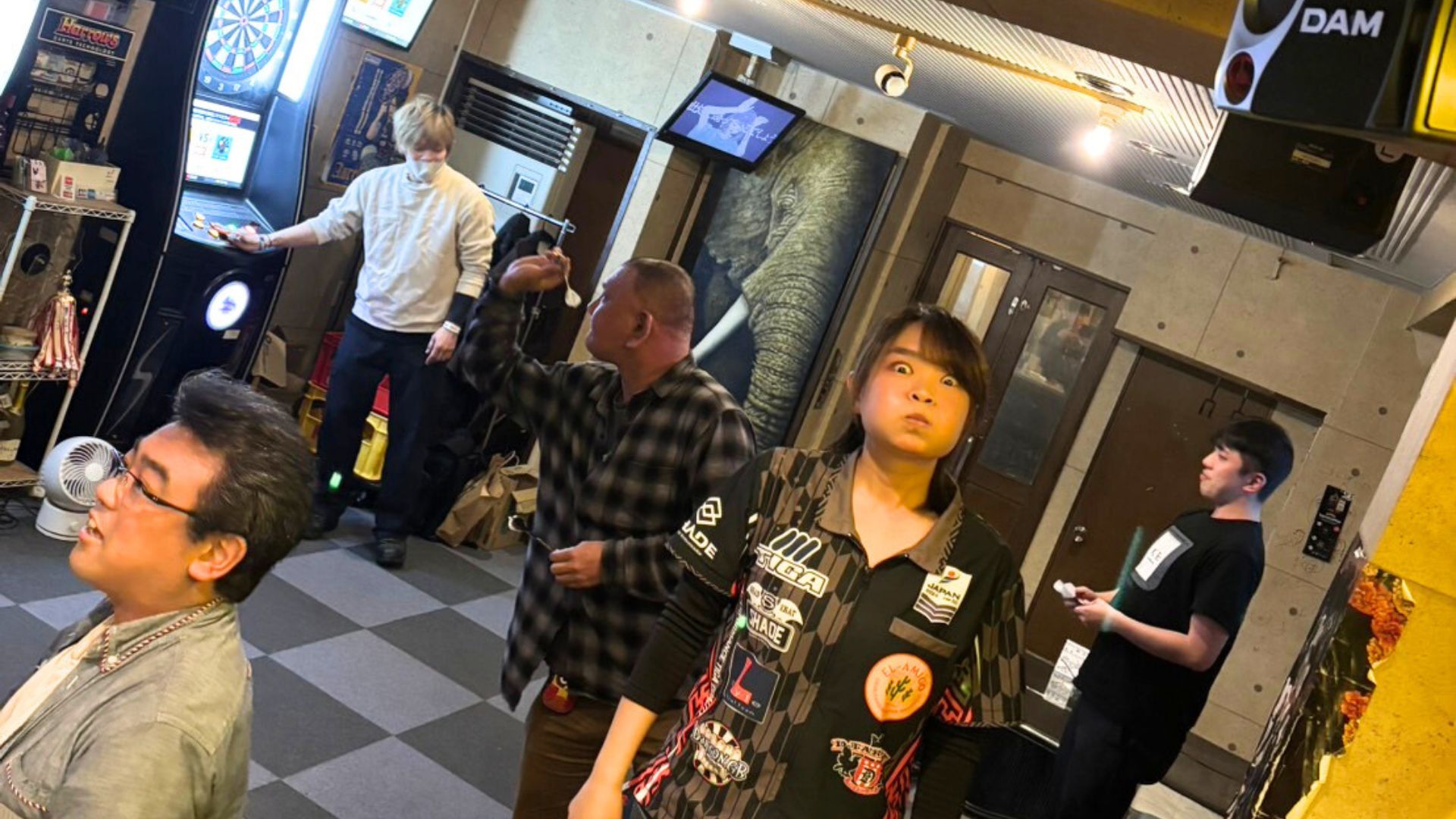 ダーツを投げるお客さんと盛り上がる店内