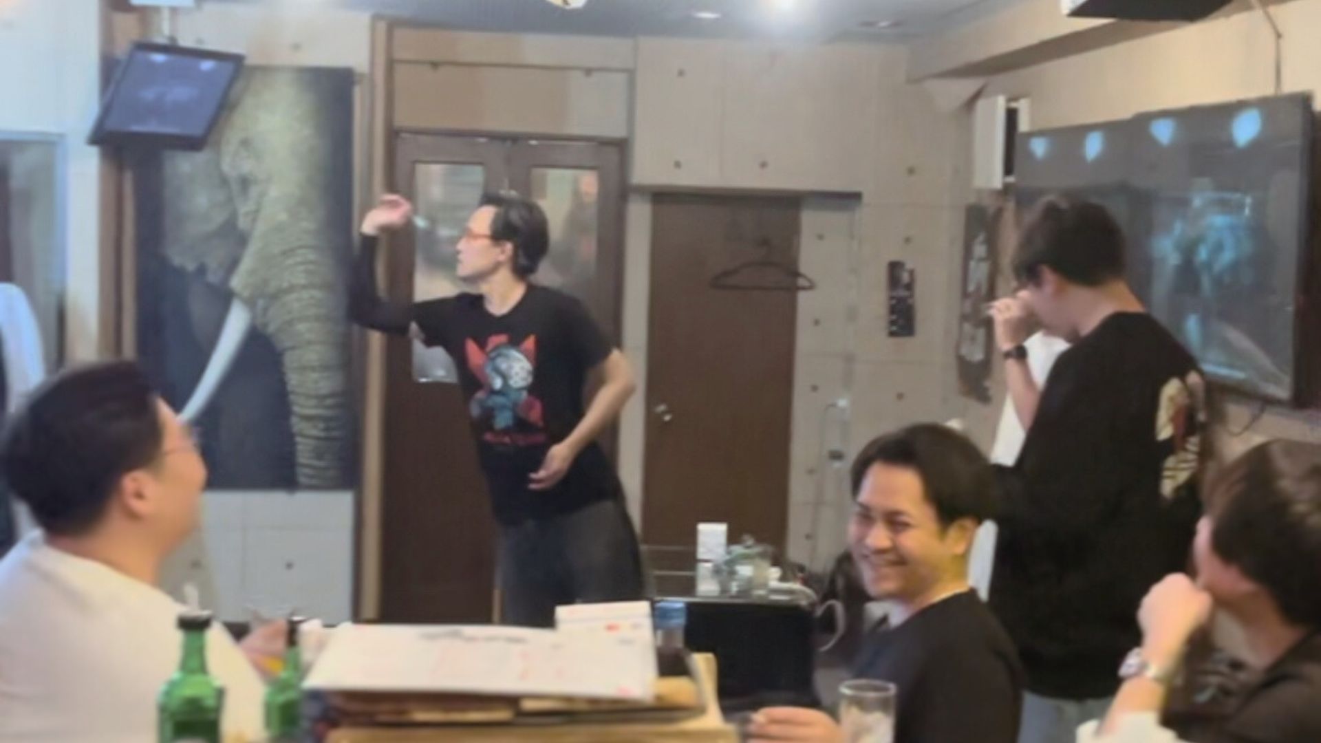 バーカウンターで談笑する人々とダーツ風景