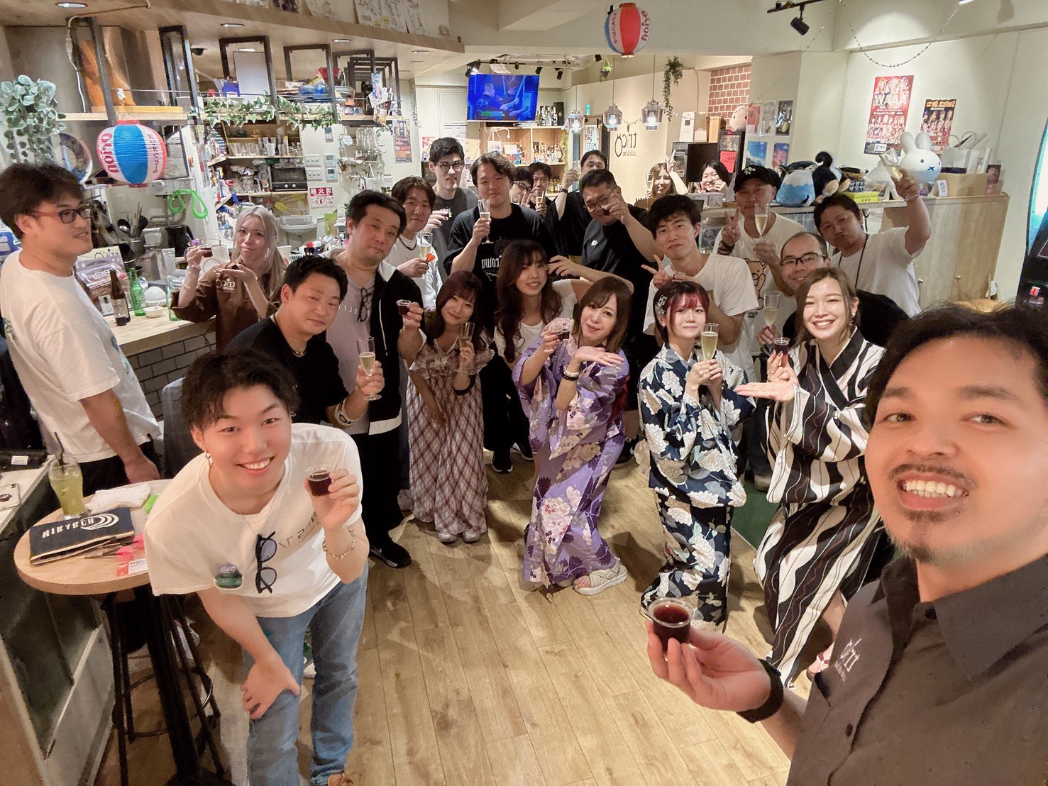 Cafe&bar tricoでのイベントの集合写真。浴衣姿のお客さんも含め、大勢がグラスを片手に笑顔で乾杯しています。