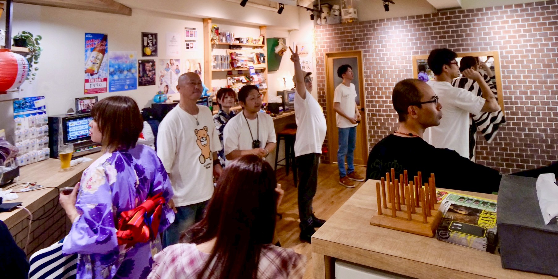 Cafe&bar tricoのカウンター席から見た店内の様子。ダーツのプレイを観戦する人々で賑わっています。